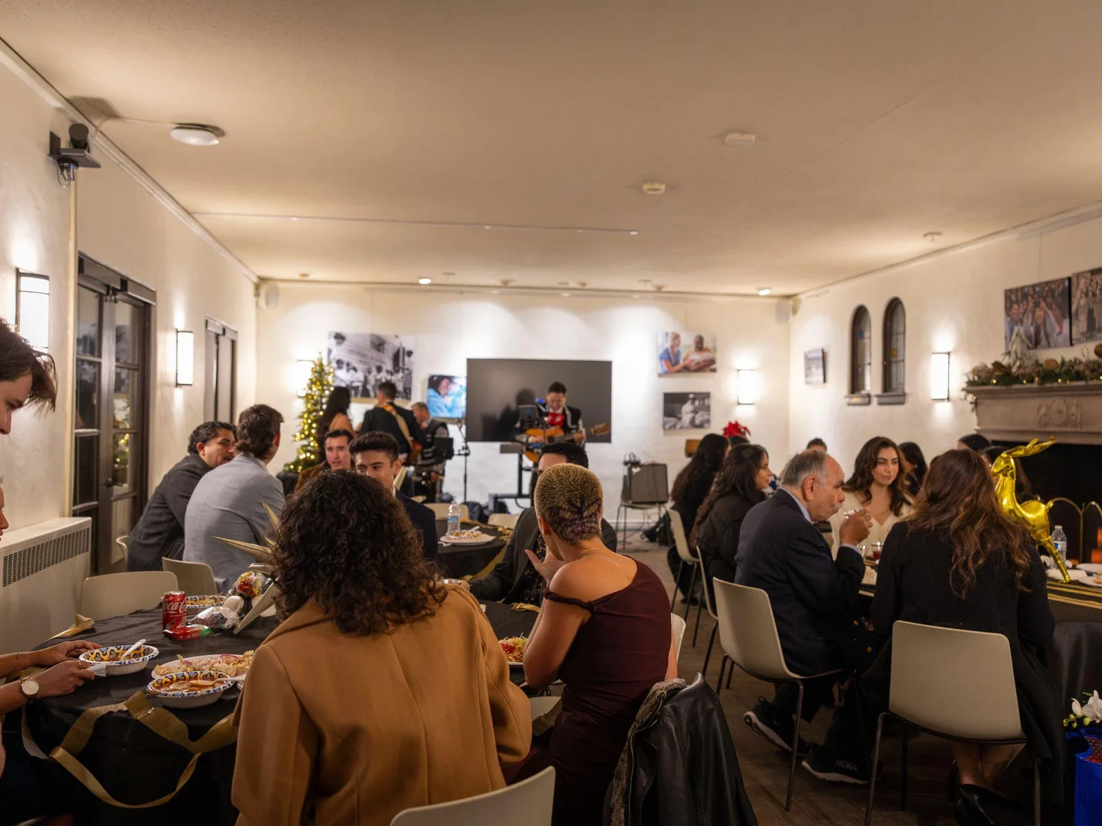 Guests dining at Winter Pachanga with a mariachi musician performing in the background.