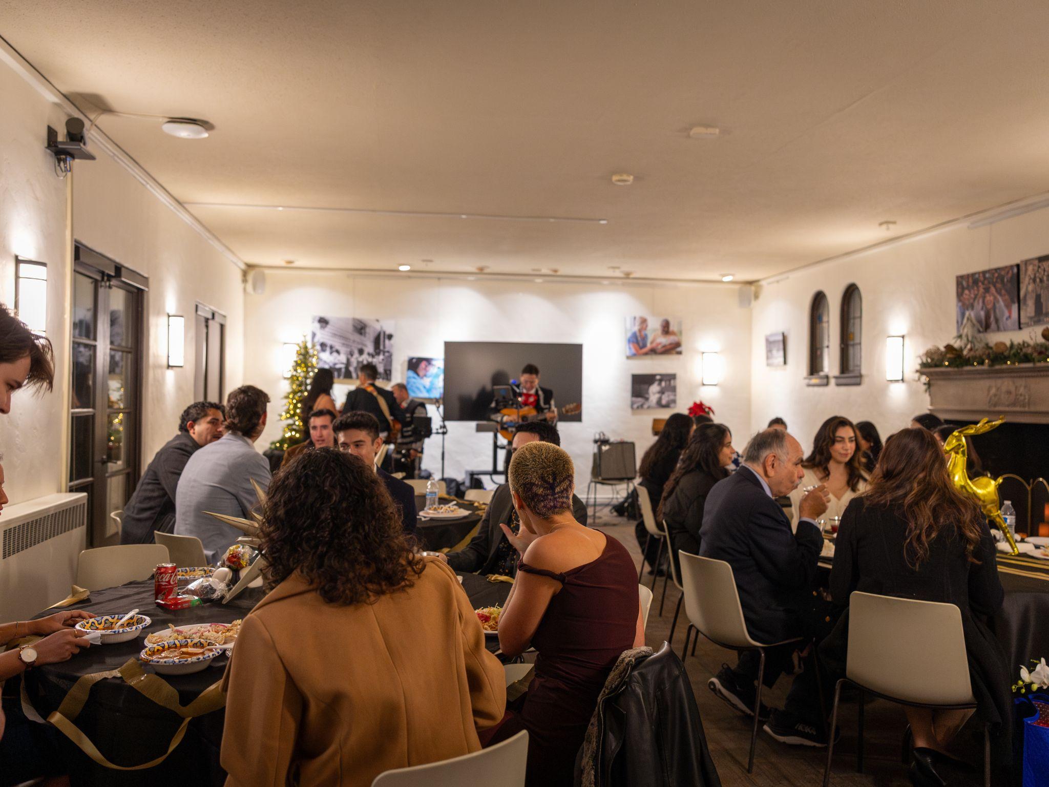 Guests dining at Winter Pachanga with a mariachi musician performing in the background.