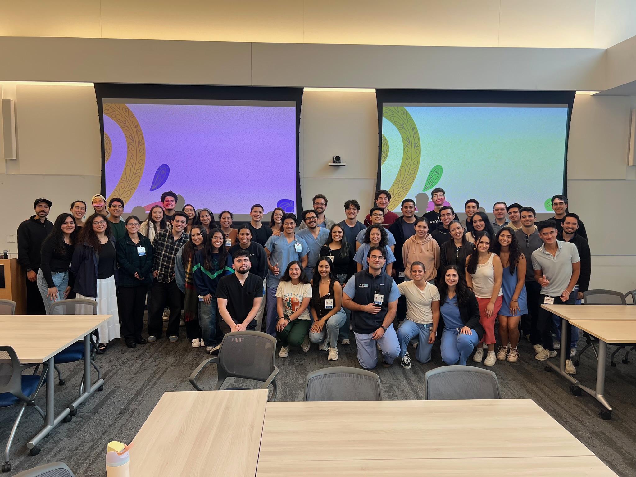 A large group of UCSF medical students and faculty gathered together in a classroom for the 2025 MS1 Welcome Dinner.