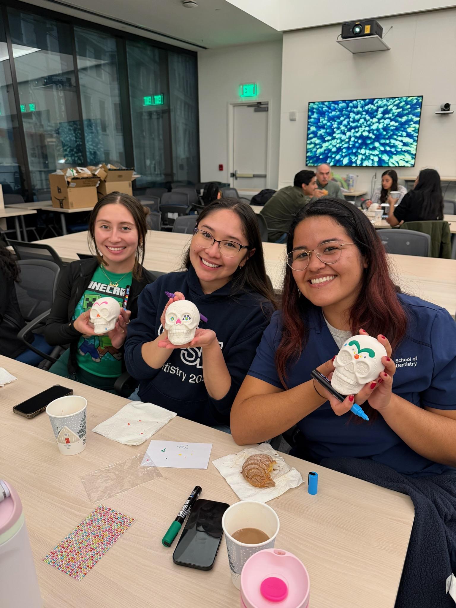 Participants painting small skull figurines at the Día de los Muertos skull decorating event.