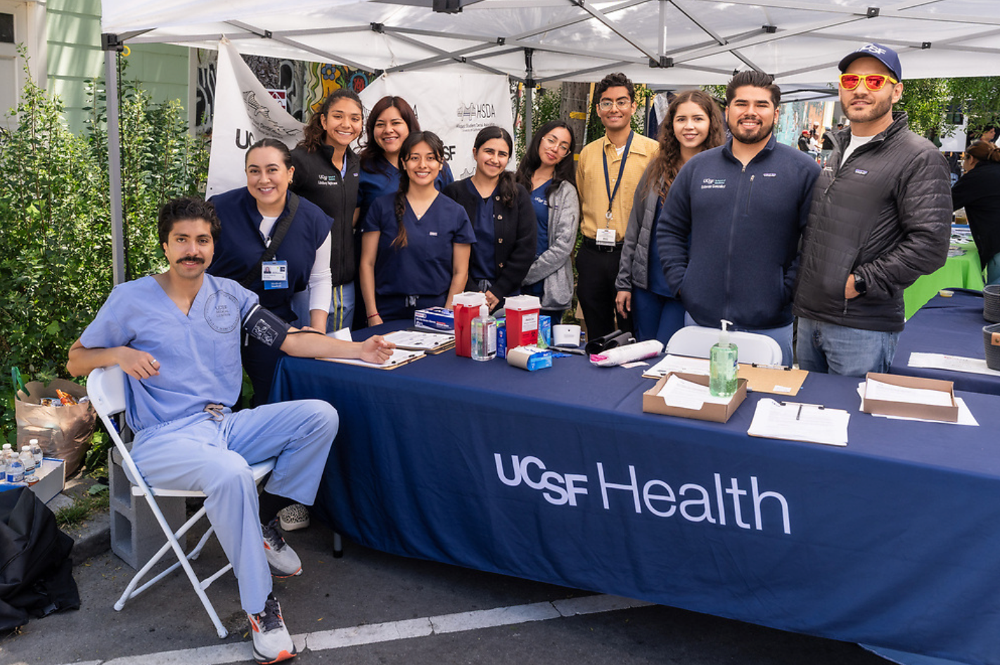 LMSA at UCSF, HSDA, and UCSF Health volunteers behind a screening table at the Carnaval health screening in the Mission District.
